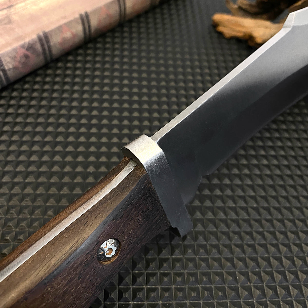 Stainless steel hunting knife with a wooden handle, paired with a black leather sheath, an essential tool for adventurers